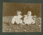 Photograph of a toddler and young girl seated on the grass, 1904