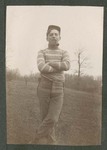 Photograph of an unidentified Miami Military Institute cadet standing on a slope near a wooded area, 1904