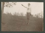 Photograph of a Miami Military Institute cadet wearing fatigue pants and school sweater, pointing a handgun, 1904