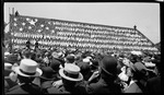 School children clothed in red, white, and blue, form an United States of America Flag in the grandstands during the 1909 Wright Brothers Homecoming Celebration medals ceremony