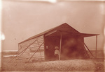 Horace Wright standing by camp building