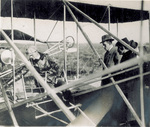 Wilbur Wright reaches toward the Flyer's engine