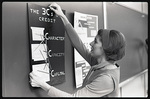 Woman hanging poster for College of Education Brochure by The Center for Teaching and Learning